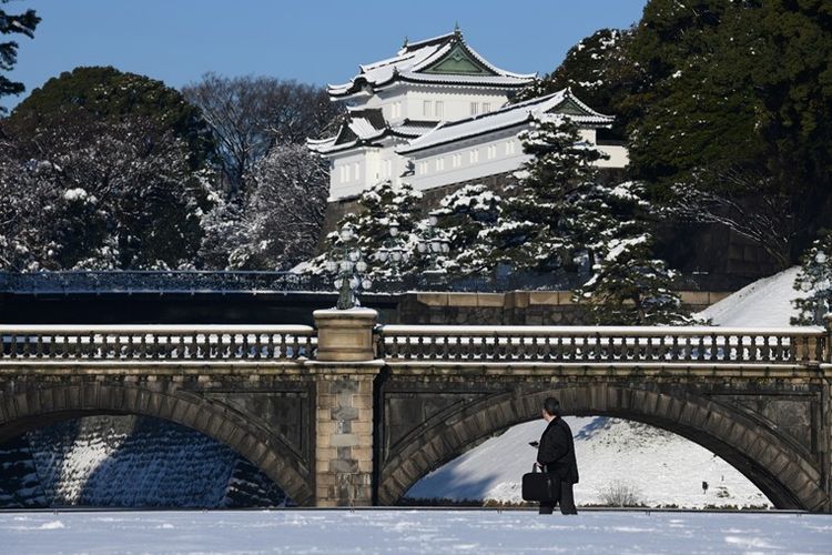 Warga melintas di depan jembatan yang tertutup salju di dekat Istana Kekaisaran di Tokyo, Selasa (23/1/2018). Suhu udara di ibu kota Jepang itu mencapai titik terendah minus 4 derajat celsius pada Kamis, (25/1/2018) yang disebut paling rendah dalam 48 tahun.