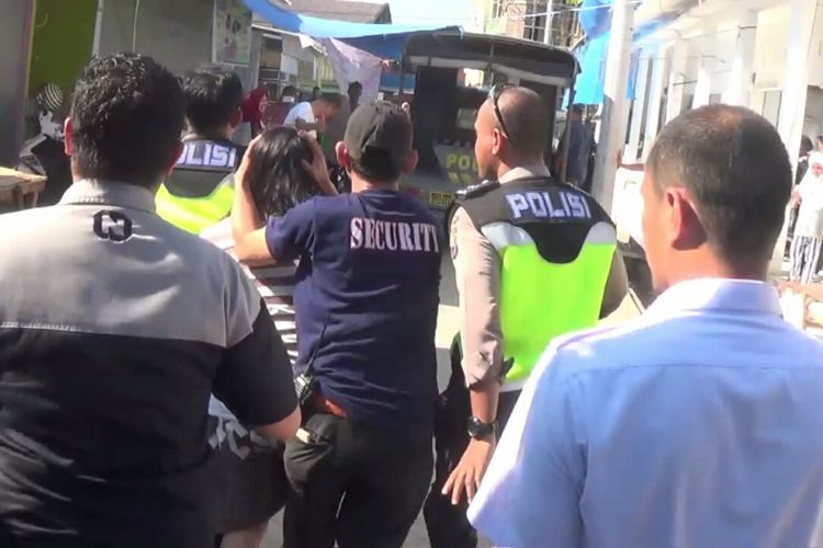 Aparat Kepolisian di Kabupaten Gowa, Sulawesi Selatan berupaya mengevakuasi seorang wanita dari amukan pengunjung pasar lantaran kepergok mencuri uang milik pedagang. Rabu, (18/7/2018). 
