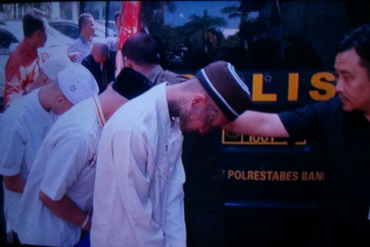 Para pelaku pengeroyokan Haringga Sirla tampak mengenakan baju koko dan kopiah tengah berjalan beriringan dikawal petugas Satreskrim Polrestabes Bandung. Ketujuh pelaku itu kini dilimpahkan ke Kejari Bandung.