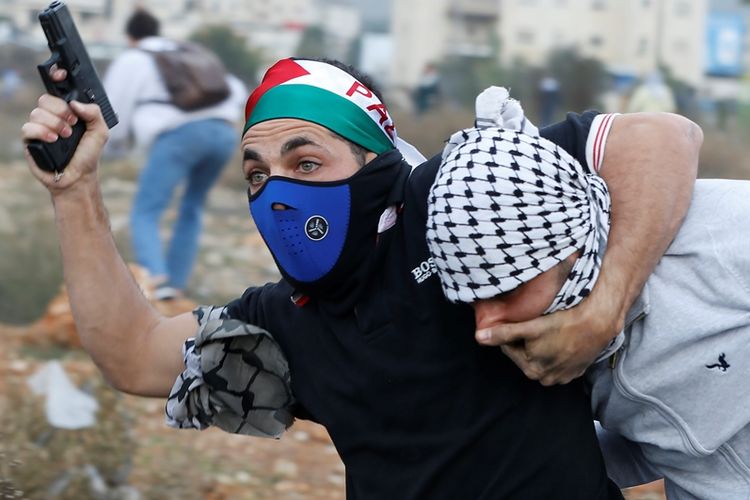 Seorang tentara Israel yang menyamar sebagai demonstran Palestina dengan bendera Palestina di kepalanya menangkap pengunjuk rasa di pos pemeriksaan DCO di Ramallah, Palestina (13/12/2017).