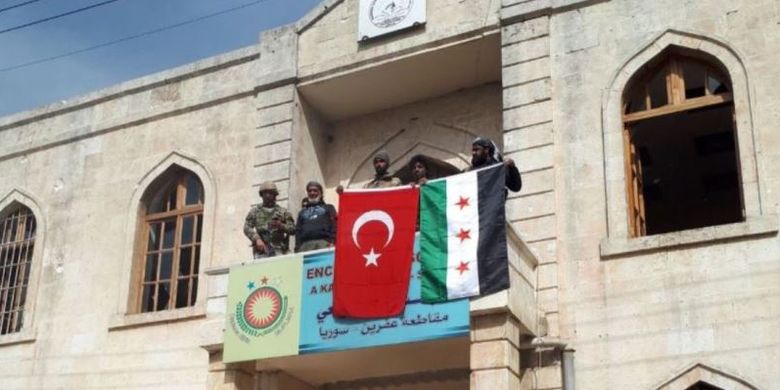 Lima orang dari pasukan pemerintah Turki dan kelompok Tentara Pembebasan Suriah (FSA) membentangkan bendera Turki dan FSA setelah merebut Afrin dari tangan Unit Perlindungan Rakyat Kurdi (YPG) Minggu (18/8/2018).