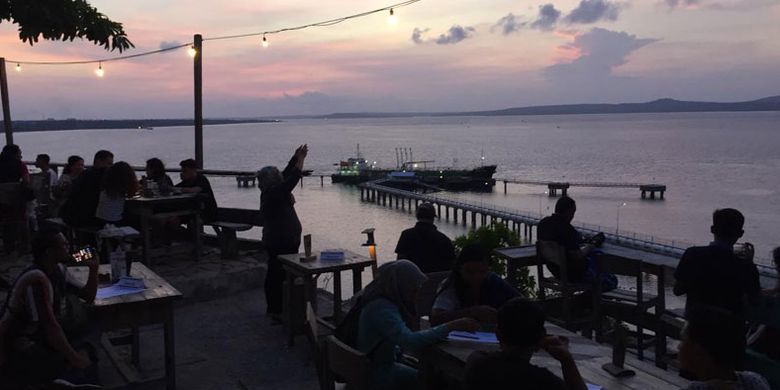 Wisatawan menikmati panorama matahari terbenam di Tebing Kafe & Bar di Kecamatan Alak, Kota Kupang, Nusa Tenggara Timur, Minggu (9/12/2018). Pemandangan matahari terbenam yang dilengkapi dengan lanskap Pelabuhan Tenau bisa jadi salah satu pilihan tempat untuk menikmati matahari terbenam.