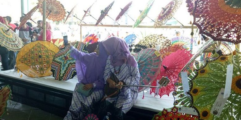 Dua orang wanita berfoto di stan payung rajut di Festival Payung 2017 di Pura Mangkunegaran Solo, Jawa Tengah, Minggu (17/9/2017).