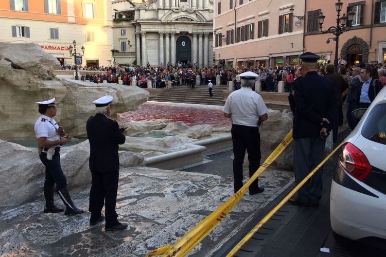 Petugas dan warga menyaksikan Air Terjun Trevi yang sudah berwarna merah karena aksi seniman bernama Graziano Cecchini. Trevi merupakan destinasi wisata paling favorit di Italia (26/10/2017)