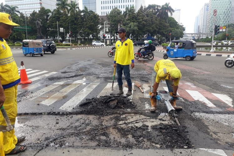 Pasukan kuning dari Suku Dinas Bina Marga Jakarta Pusat memperbaiki Jalan MH Thamrin sekitar Patung Kuda yang berlubang, Kamis (10/1/2019).