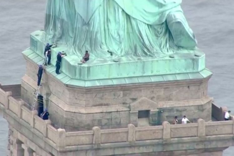 Polisi sedang berbicara dengan seorang perempuan yang naik ke Patung Liberty di New York pada Rabu (4/7/2018). (AFP/PIX11 News)