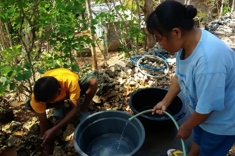 Minem dan beberapa orang warga Dusun Legundi, Desa Planjan, Kecamatan Saptosari, Gunungkidul, mengais air sisa pipa PDAM yang bocor, Senin (20/8/2018)