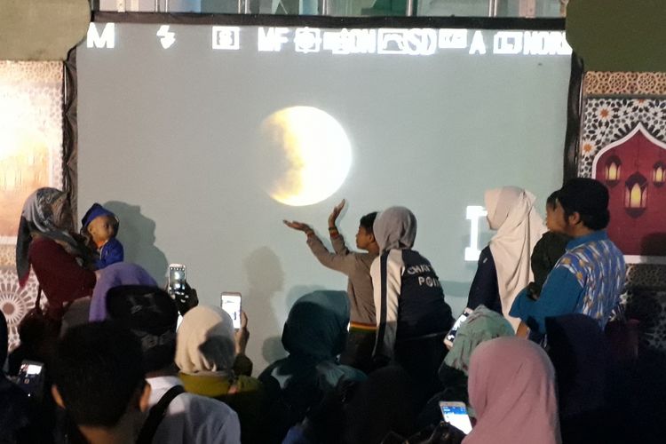 Warga berpose di spot foto gerhana bulan di Masjid Al-Akbar Surabaya.