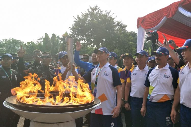 Legenda bulutangkis Indonesia Christian Hadinata membawa obor Asian Games di Taman Margasatwa Ragunan, Jakarta Selatan, Rabu (15/8/2018).