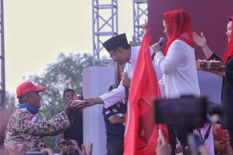 Calon Gubernur Jawa Timur Saifullah Yusuf atau Gus Ipul saat memberikan kue ulang tahun Presiden Joko Widodo untuk seorang kader Partai Gerindra. Momen tersebut terjadi saat kampanye akbar pasangan Gus Ipul-Puti Guntur Soekarno di Lapangan Gulun, Madiun, Jawa Timur, Kamis (21/6/2018).