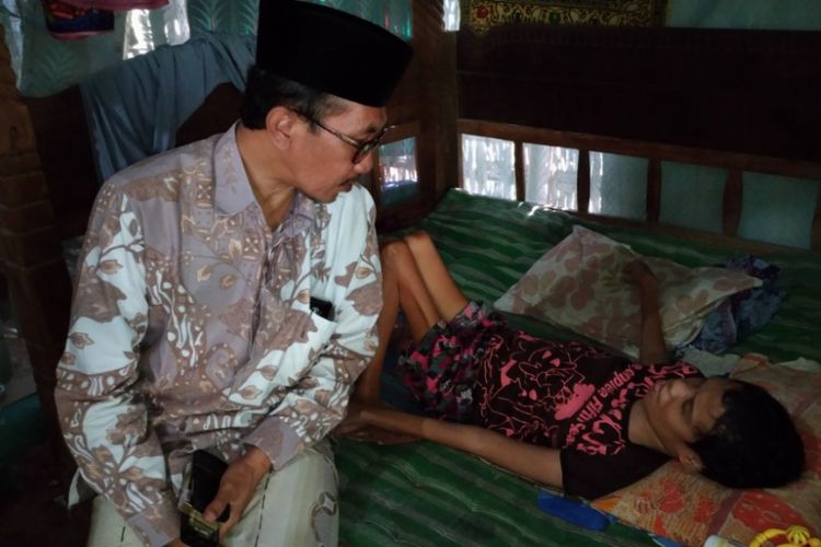 Salah satu anak Atmani tergeletak di ranjang kayu karena lumpuh sejak lahir