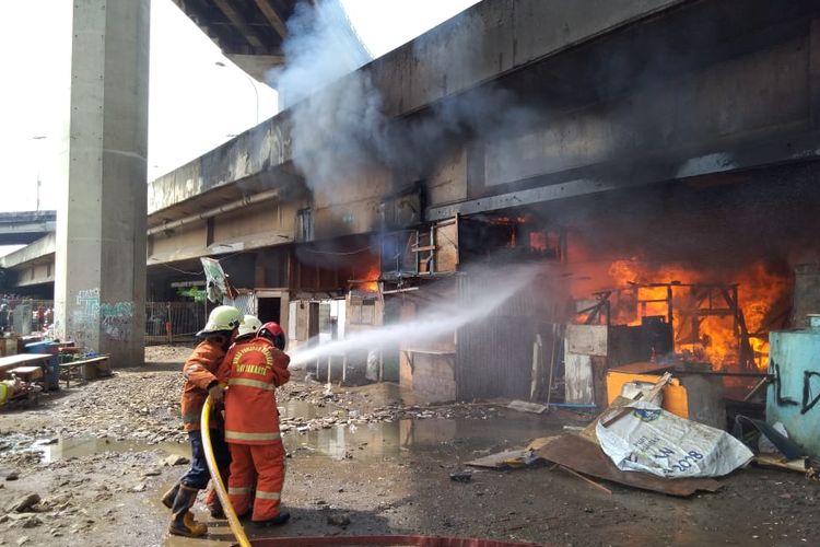 Petugas berupaya memadamkan api yang melalap lapak-lapak di kolong Tol Pluit, Jakarta Utara, Sabtu (30/3/2019).