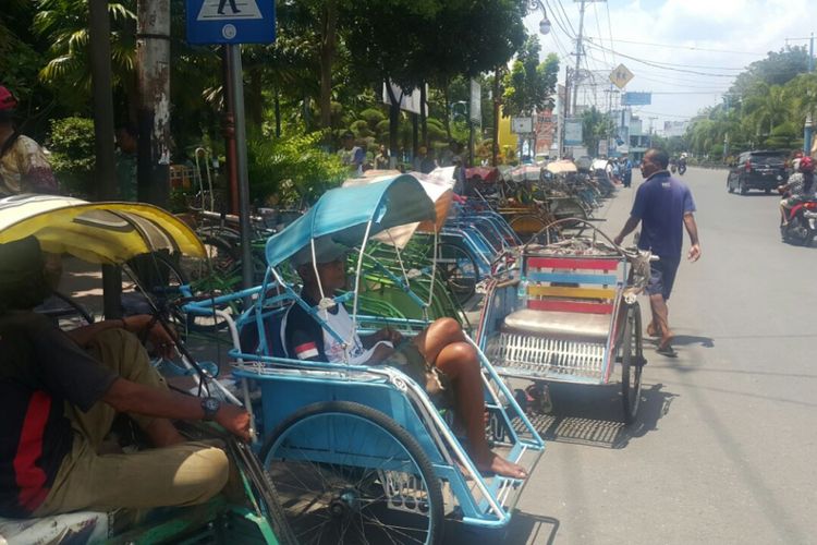 Ratusan tukang becak menunggu kedatangan Presiden Jokowi yang akan memberikan bantuan sembako kepada mereka di Alun-alun Kota Madiun, Kamis (29/3/2018) siang.