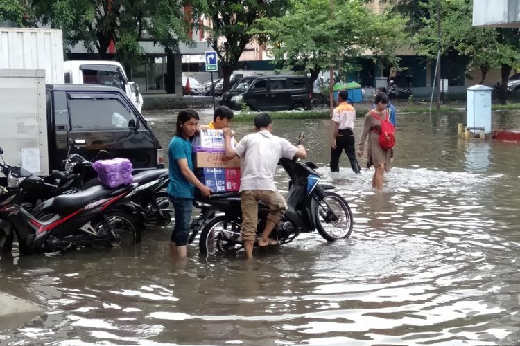 Aktivitas bekerja di tengah banjir di ruko Grosir Tekstil, Mangga Dua, Jakarta Utara, Selasa (5/3/2019)