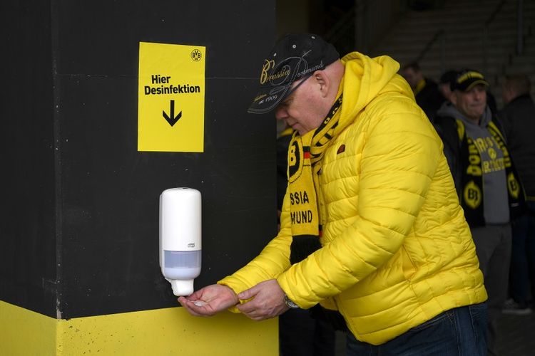 Seorang suporter membersihkan tangannya pada pertandingan sepak bola Bundesliga antara Borussia Dortmund vs SC Freiburg pada 29 Februari 2020 di Dortmund.