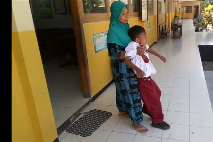 Nampak Tutik mengangkat anaknya Fatta yang mengalami kelumpuhan total pada kedua kakinya sejak kecil. Kendati lumpuh, Fatta memiliki tekad luar biasa mengenyam pendidikan di SDN di Desa Coper, Kecamatan Jetis, Kabupaten Ponorogo.