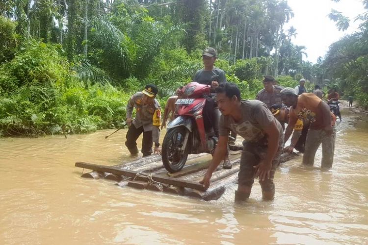 Polisi membantu warga melewati banjir di Desa Pante Labu, Kecamatan Pante Bidari, Kabupaten Aceh Timur terendam banjir, Senin (19/11/2018).
