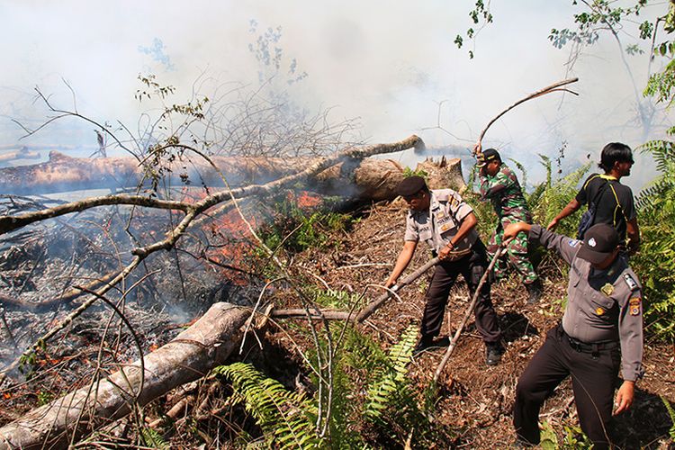 Polisi melakukan upaya pemadaman kebakaran lahan gambut yang terjadi di kawasan Desa Leuhan, Kecamatan Johan Pahlawan Kabupaten Aceh Barat, Senin (31/7/17).