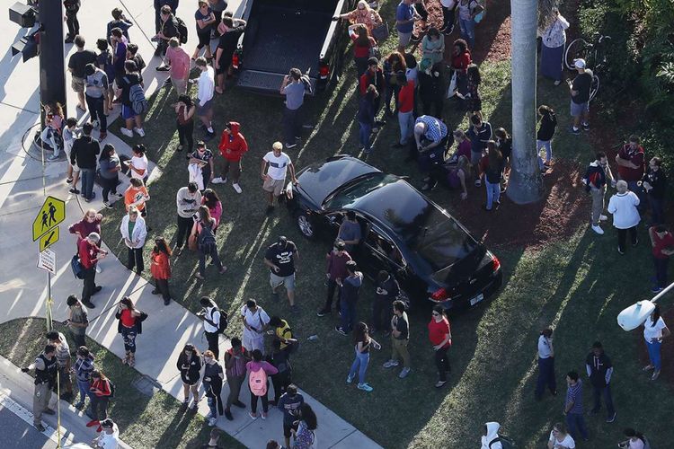 Sejumlah orang menunggu di luar gedung sekolah menyusul terjadinya insiden penembakan di SMA Marjory Stoneman Douglas, di Parkland, Florida, Amerika Serikat, Rabu (14/2/2018). Insiden yang menewaskan 17 orang itu dilakukan oleh Nikolaus Cruz (19) yang juga merupakan mantan murid sekolah tersebut.