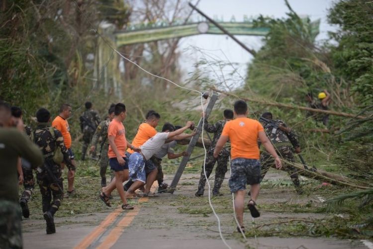 Petugas penyelamat membersihkan jalan dari puing-puing yang disebabkan oleh angin kencang siklon tropis Mangkhut di kota Baggao di provinsi Cagayan, sebelah utara Manila, Filipina, Sabtu (15/9/2018). (AFP/Ted Aljibe)