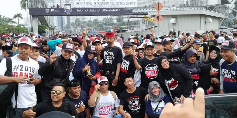 Sejumlah warga tampak memakai baju dan kaus #2019GantiPresiden di Bundaran HI, Jakarta, Minggu (29/4/2018).