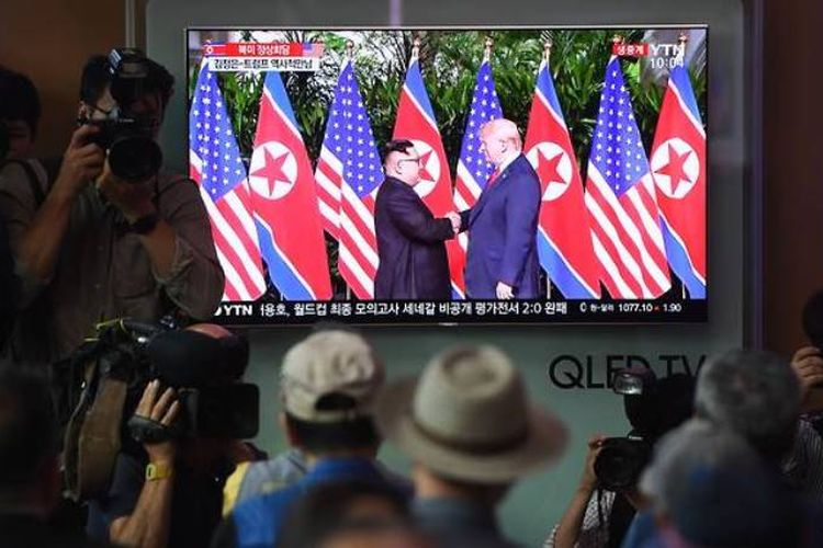 Warga berkumpul di stasiun kereta api di Seoul untuk menyaksikan siaran langsung pertemuan antara Presiden Trump dengan Kim Jong Un, Selasa (12/6/2018).