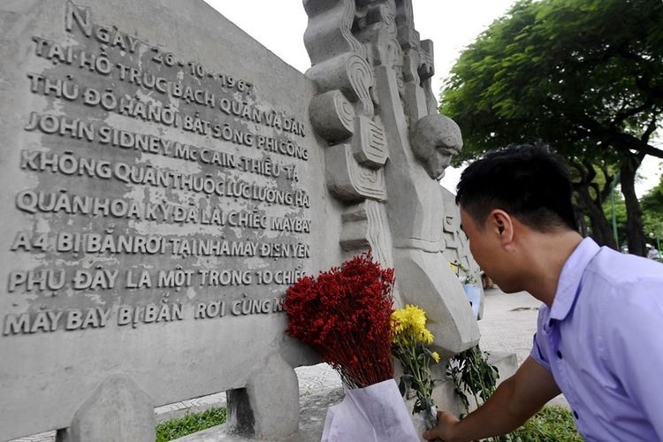 Seorang warga Vietnam meletakkan bunga sebagai penghormatan kepada mendiang Senator AS John McCain di memorial Perang Vietnam di dekat Danau Truc Bach, Minggu (26/8/2018).