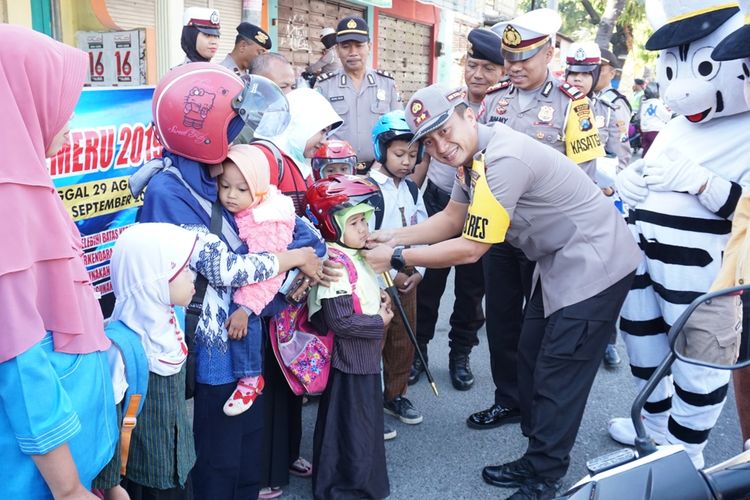 BERIKAN HELM--Kapolres Madiun, AKBP Ruruh Wicaksono memberikan helm gratis bagi anak-anak yang terjaring dalam operasi patuh 2019 di ruas jalan Madiun-Ponorogo, Kecamatan Dolopo, Kabupaten Madiun, Kamis ( 5/9/2019) siang.
