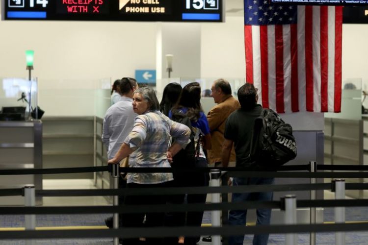 Para penumpang pesawat yang memasuki AS mengantre di tempat pemeriksaan Bea Cukai dan Perlindungan Perbatasan (CBP) setibanya di bandara international Miami, Florida.