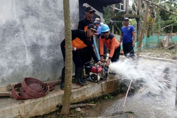 Petugas BPBD Cilacap menurunkan pompa pemadam kebakaran untuk menguras sumur warga Dusun Margasari, Desa Madura, Kecamatan Wanareja, Cilacap, Jawa Tengah yang tercemar akibat banjir luapan Sungai Cipaganjing, Selasa (21/11/2017).