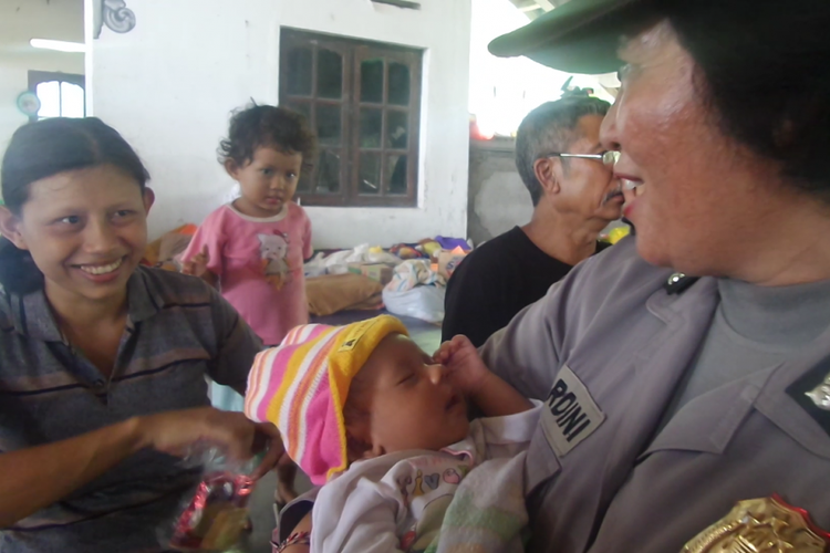 Kadek Tantri Wulandari, bayi berusia satu bulan yang lahir di pengungsian Gunung Agung terlihat tenang digendong polwan.