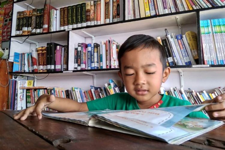 Seorang anak membaca di Kafe Literasi, Desa Ujong Blang, Kecamatan Banda Sakti, Kota Lhokseumawe, Aceh, Minggu (15/7/2018).
