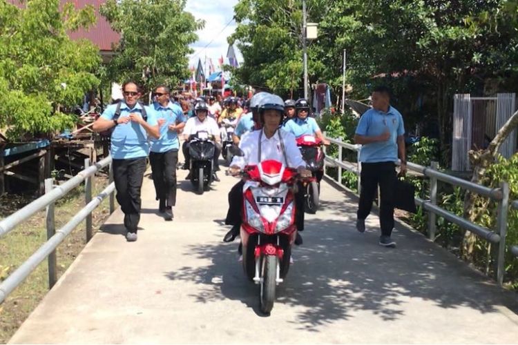 Presiden Joko Widodo dan Ibu Negara menaiki motor listrik saat blusukan di jalanan Kota Agats, Kabupaten Asmat, Provinsi Papua, Kamis (12/4/2018).