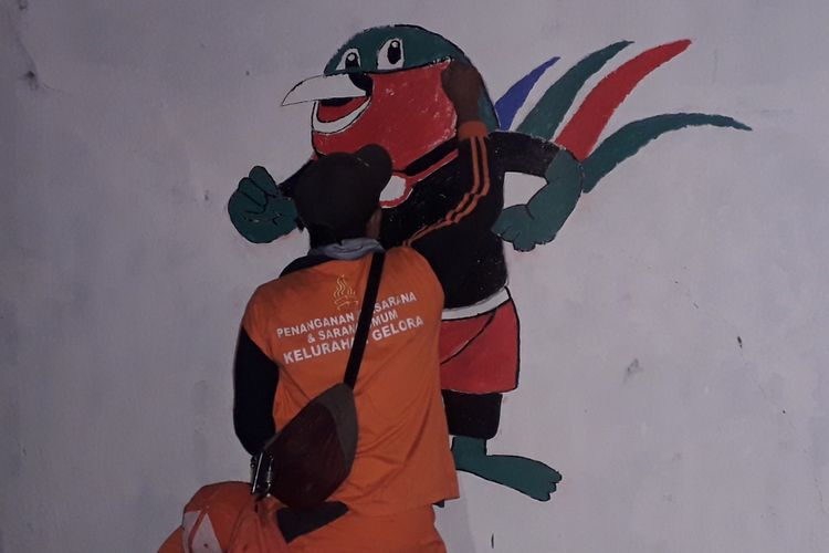 Petugas PPSU menggambar maskot Asian Games di tembok lapangan tembak Gelora Senayan, Kamis (19/7/2018)