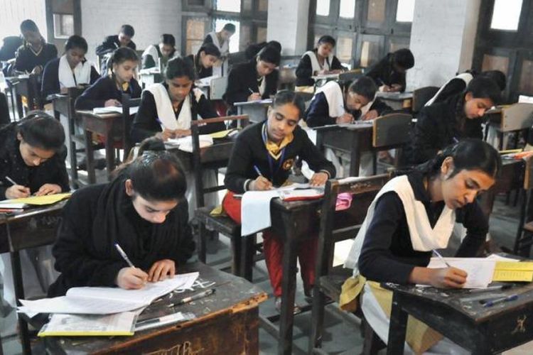 Siswi Kelas 12 tampak serius mengerjakan soal ujian di Negara Bagian Uttar Pradesh, India.