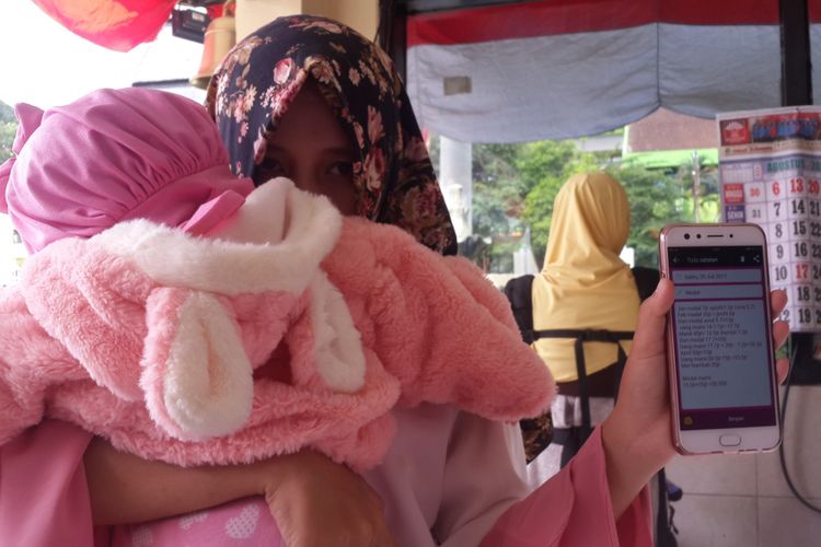 Salah satu korban investasi bodong, Fitri (21) sambil menggendong anaknya saat menunjukkan bukti uang yang diinvestasikannya di Mapolres Malang Kota, Rabu (2/8/2017)