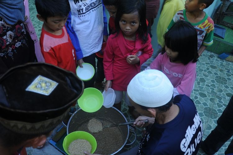 Kartibi membagikan bubur syuro kepada anak-anak serta warga di sekitar masjid Suro Jalan Ki Gede Ing Suro, Kelurahan 30 Ilir Kecamatan Ilir Barat II, Palembang Sumatera Selatan, Rabu (8/5/2019). Bubur Syuro ini, selalu disiapkan secara gratis ketika memasuki bulan ramadhan.
