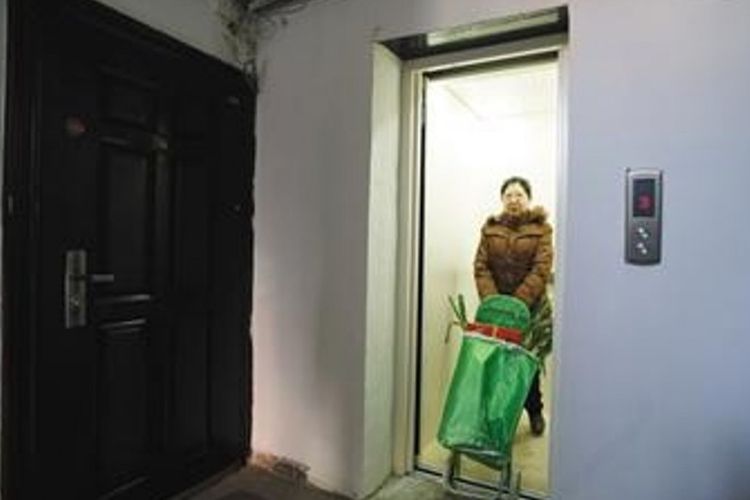 Penghuni gedung menggunakan fasilitas lift yang baru-baru ini dipasang di apartemen tempat tinggalnya di China.