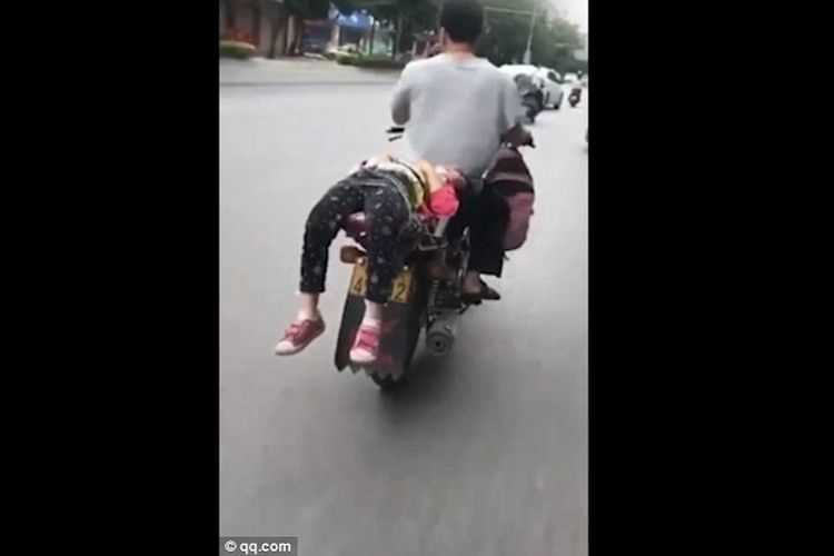 Foto yang diambil dari video ini memperlihatkan seorang pria di China mengikat anaknya di bagian belakang sepeda motor dan melaju di jalan raya.
