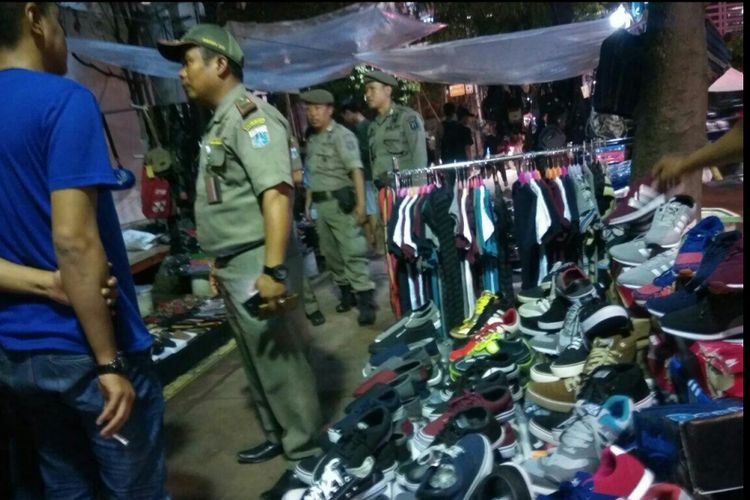 Petugas Satpol PP terlihat berada di lokasi PKL berjualan di atas trotoar Jalan Sudirman, dekat Halte Bendungan Hilir, Jakarta Pusat, Selasa (30/1/2018) malam.