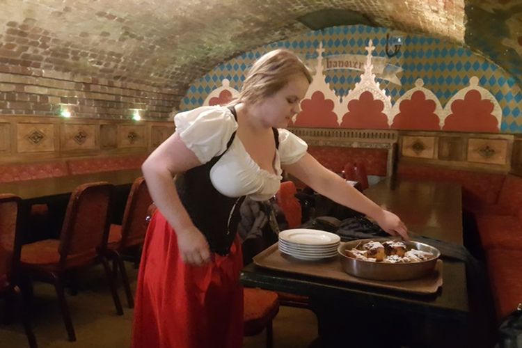 Pelayan di The Medieval Banquet di St Khatarine Pier menyajikan apple bread pudding.