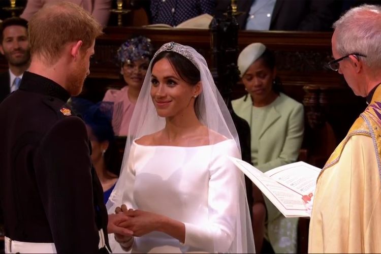 Meghan Markle menyematkan cincin pernikahan ke jari manis Pangeran Harry dalam prosesi pemberkatan nikah di Kapel St.George, Windsor, Inggris, Sabtu (19/5/2018).    