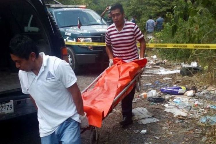 Dua petugas polisi Veracruz mengangkat jenazah tanpa kepala yang menjadi korban pembunuhan kartel narkoba di sana.
