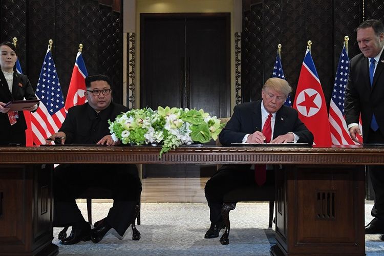 US President Donald Trump (2nd R) and North Koreas leader Kim Jong Un (2nd L) sign documents as US Secretary of State Mike Pompeo (R) and the North Korean leaders sister Kim Yo Jong (L) look on at a signing ceremony during their historic US-North Korea summit, at the Capella Hotel on Sentosa island in Singapore on June 12, 2018.

Donald Trump and Kim Jong Un became on June 12 the first sitting US and North Korean leaders to meet, shake hands and negotiate to end a decades-old nuclear stand-off. / AFP PHOTO / SAUL LOEB