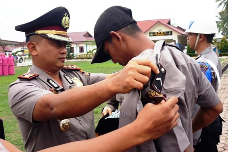 Kapolres Aceh Timur AKBP Rudi Purwiyanto membuka baju seragam Polri dari seorang personel yang diberhentikan dengan tidak hormat dalam sebuah upacara di  halaman Mapolres Aceh Timur, Rabu (8/3/2018). 
