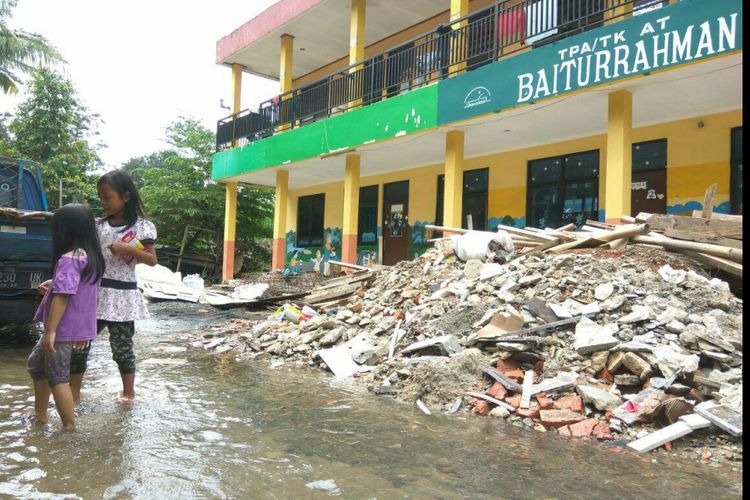 Anak-anak asik bermain di luapan air dari kali yang mengalir di belakang TK dan Masjid Baiturrahman, Tapos, Kota Depok, Rabu (7/2/2018).