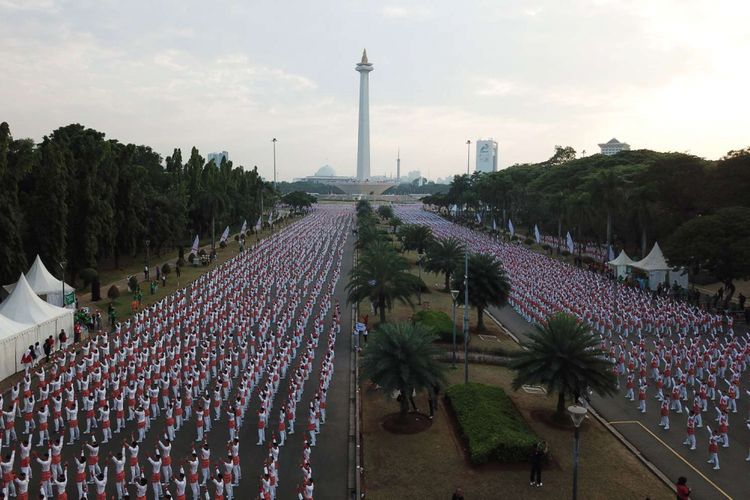 Ribuan warga melakukan senam poco-poco saat menyusun rekor dunia senam massal poco-poco di Monas, Jakarta, Minggu (5/8/2018).  Kegiatan dalam rangka menyambut Asian Games 2018 itu diikuti 65 ribu peserta dari berbagai kalangan.
