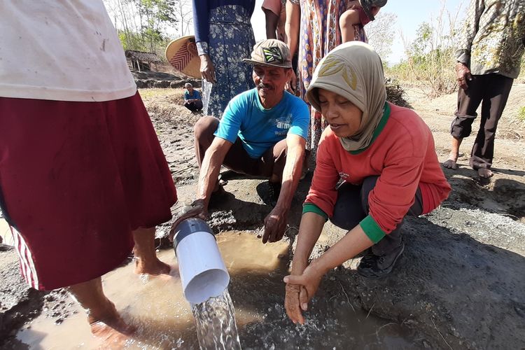 Suyadi (berkaus biru) bersama warga memanfaatkan air bersih yang tiba-tiba keluar dari ladang tandus di Widoro Lor, Desa Bendung, Semin, Gunungkidul, Yogyakarta, Rabu (21/8/2019).