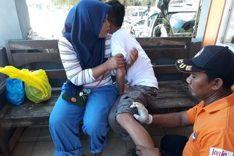 Petugas SAR Satlinmas Wilayah II Gunungkidul Membantu Wisatawan yang Tersengat Ubur-ubur di Pos SAR Pantai Sepanjang Kamis (6/6/2019).
