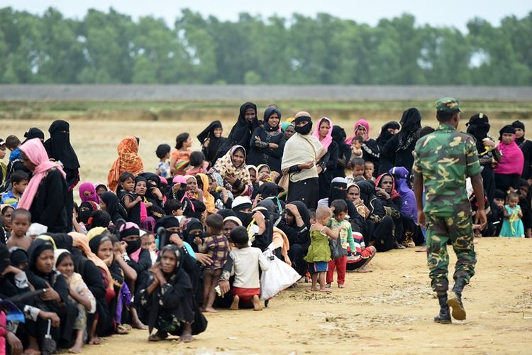 Tentara Bangladesh berjalan di depan para pengungsi Rohingya di kamp Nayapara di Teknaf, Oktober 2017.